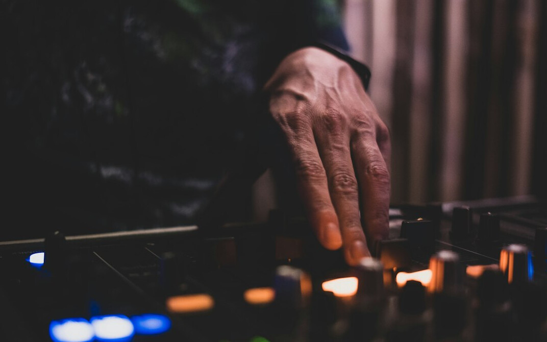 Sound engineer's hands adjusting mixing console sliders